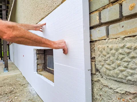 Rigid foam board insulation panel being fitted to an exterior wall